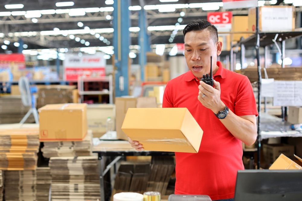 Man in a warehouse holding a two-way radio with a long range